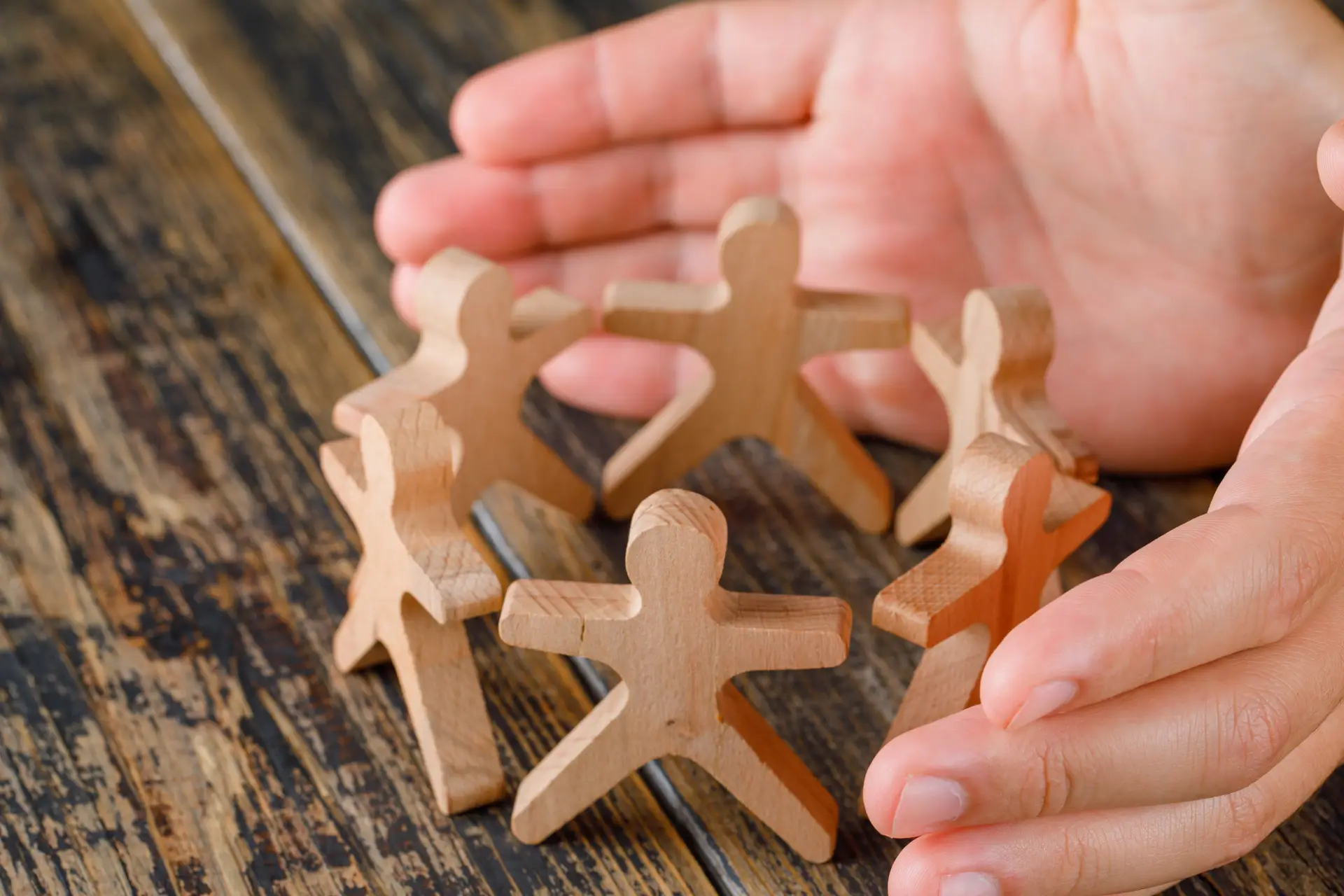business-success-concept-wooden-table-top-view-hands-protecting-wooden-figures-people